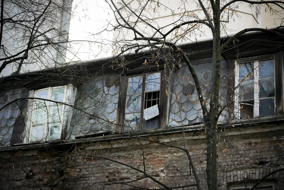 Broken upper-floor windows in a crumbling brick building